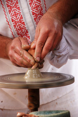 Close up of craftsmen hand showing child how to do pottery