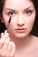Beautiful brunette applying mascara/makeup