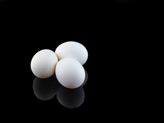 Three white eggs on black background.
