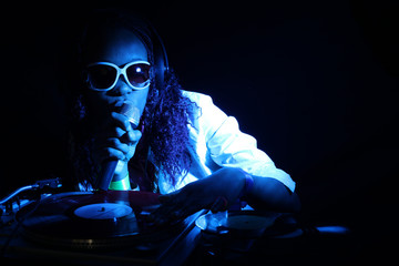 cool afro american DJ with mic in action under blue light