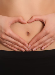 Woman's hands around her navel in a heart shape