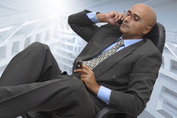 Businessman at the phone, sitting on a chair