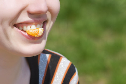 Smiling mouth with piece of mandarin orange