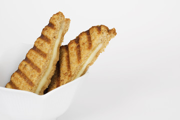 Grilled cheese sandwich in white bowl. Wholewheat bread.