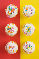 Delicious cupcakes on split red and yellow background