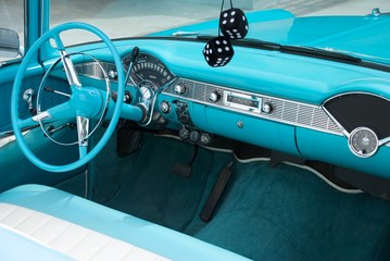 Interior shot of a blue colored 1956 convertible with fuzzy dice