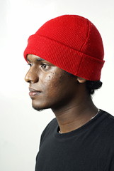 Indian man side portrait with red beanie hat on white
