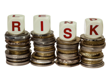 Stacks of coins with the word RISK isolated on white