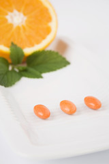 Yellow pills on white plate with orange
