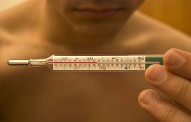 Young man checking thermometer with high temperature