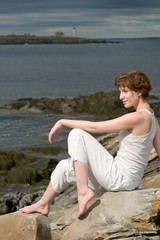 Pensive beautiful young woman, outdoors on a rocky beach
