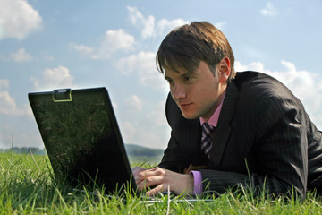 Businessman working with a laptop outdoor on grass