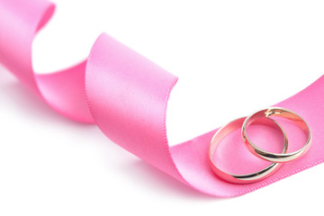 Golden wedding rings over pink ribbon isolated
