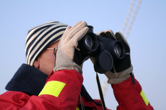 Segler blickt durch ein Fernglas