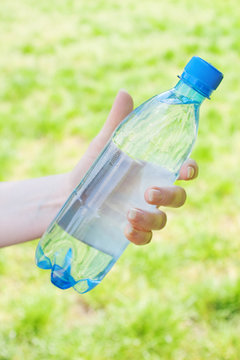 Closeup of hand offering blue bottle of water