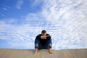 Fototapeta na wymiar A man sitting on top of a sand dune