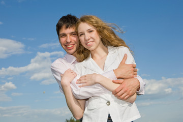 Young love couple smiling under blue sky