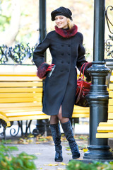 Beautiful blonde in coat and hat standing outdoors