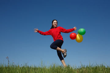 Girl holding balloons running outdoor
