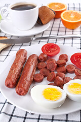breakfast meal with sausages, boiled eggs, oranges and coffee