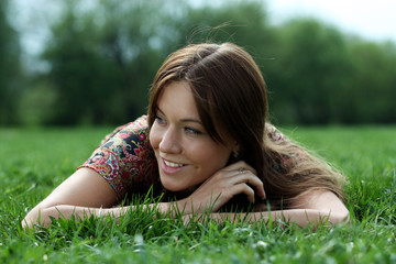 Young beautiful woman lays on green field