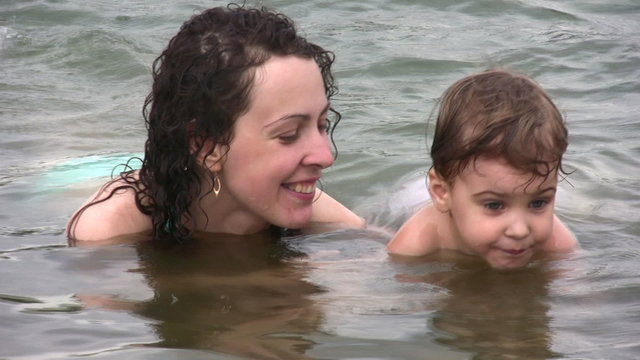 mother kissing little girl swim