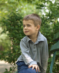 Boy sitting in the park and  leering one’s eye at camera