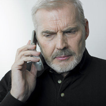 homme m&ucirc;r contrari&eacute; au t&eacute;l&eacute;phone