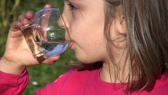 fillette buvant un verre d'eau en gros plan