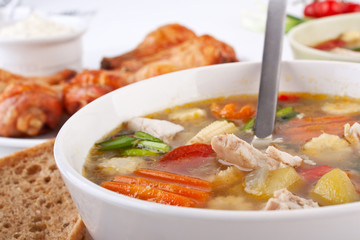 serving of chicken and vegetable soup with chicken legs