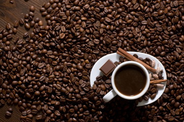 Cup of coffee with chocolate on coffee beans, view from above