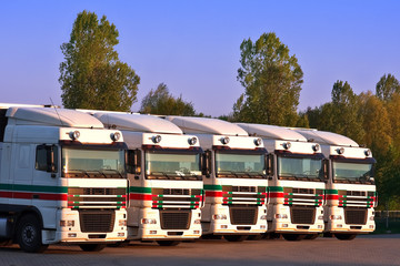 five trucks in a row with trees and blue sky in the background