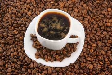 White cup of coffee on coffee grains background