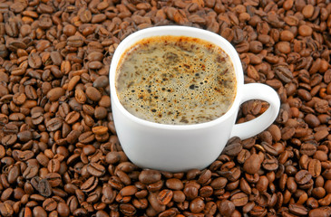 White cup of coffee on coffee grains background