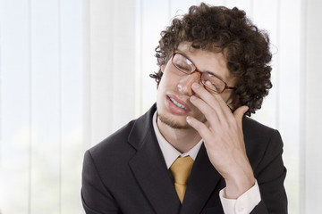 Man in business suit massaging his eye