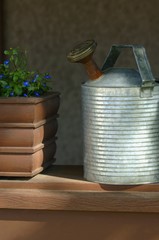 Metal watering can beside planter