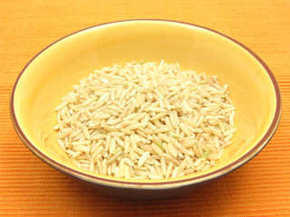 Keramikschale mit Naturreis vor orangem Hintergrund