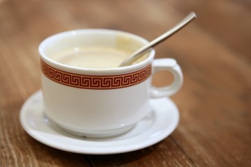 Coffe with milk white cup over teak wooden