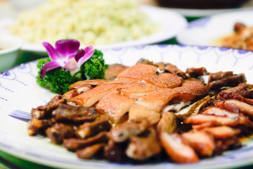 sliced roasted pork on white plate decorated with orchid
