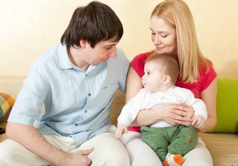 Young happy family sitting on sofa at home