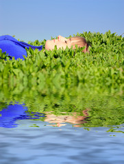 The girl sleeps in a grass near water