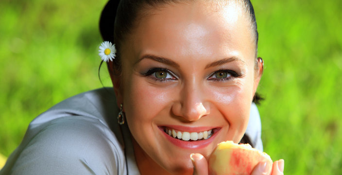 Woman With Flower Behind Is Eating A Peach Fruit