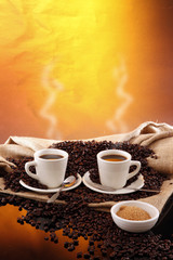 Hot cups of fresh brewed coffee and grains from a sisal sack