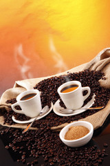 Hot cups of fresh brewed coffee and grains from a sisal sack