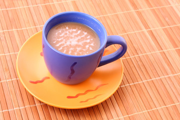 Coffee with milk color cup on bamboo straws background
