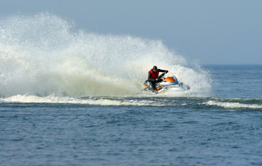 Jet ski in action with water spray on the blue sea