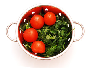 arugula and tomatoes in stainless steel stainer