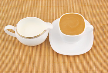 White cup of coffee and milk jug