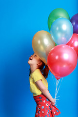 Fototapeta na wymiar little girl holding colorful balloons on a blue background