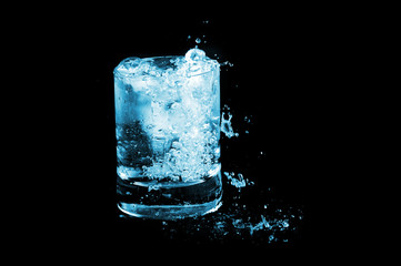 Ice in glass and water splash  on black background